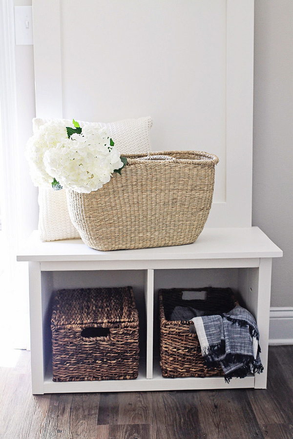 Hall Tree bench seat with wicker basket on top filled with white hydrangea flowers