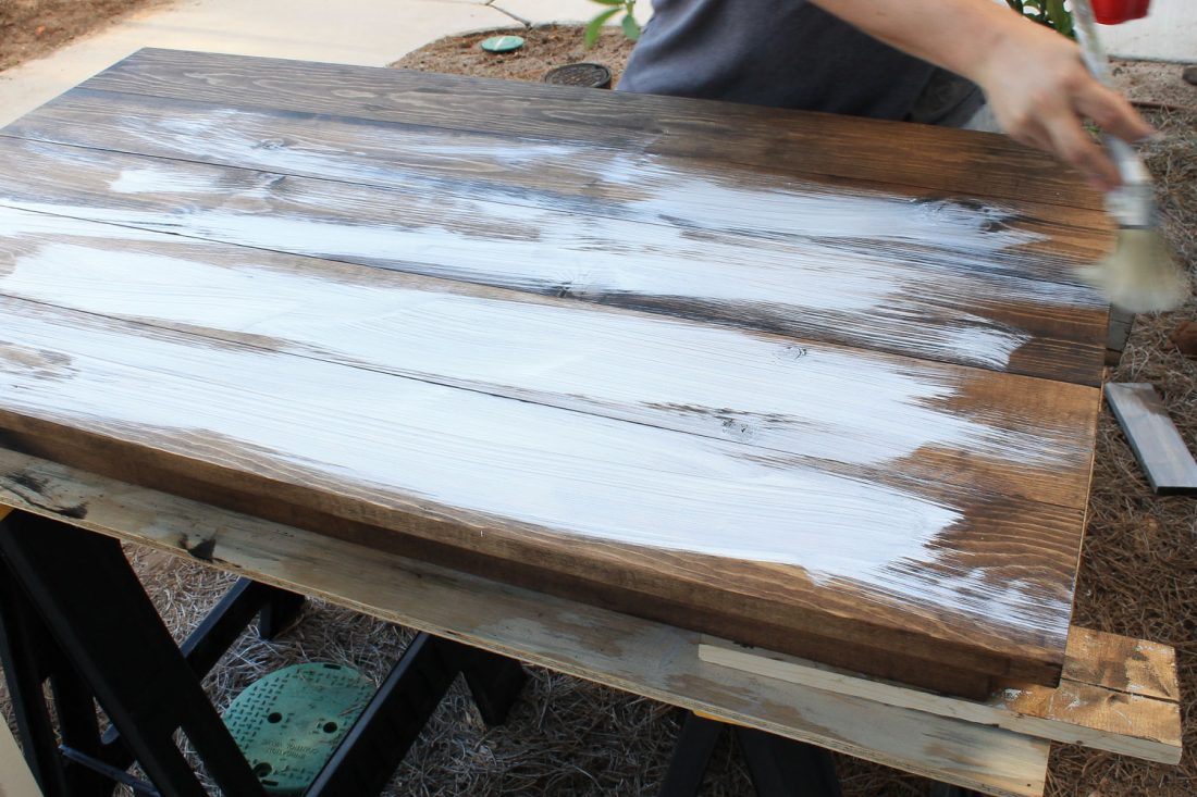 using a paint brush to grey wash wood on stained wood desk top