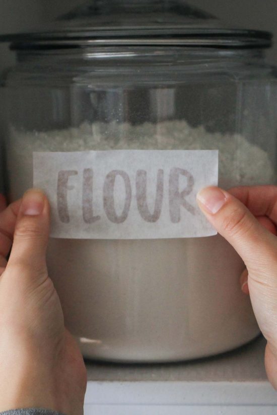 applying vinyl DIY pantry label decal to flour jar