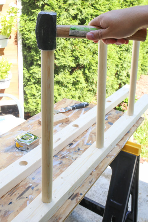 hammering dowel rods into drilled holes for how to build a blanket ladder