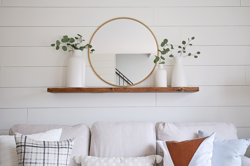 DIY wood Floating Shelf with modern round bras mirror, white ceramic vases, and ecualyptus branches 