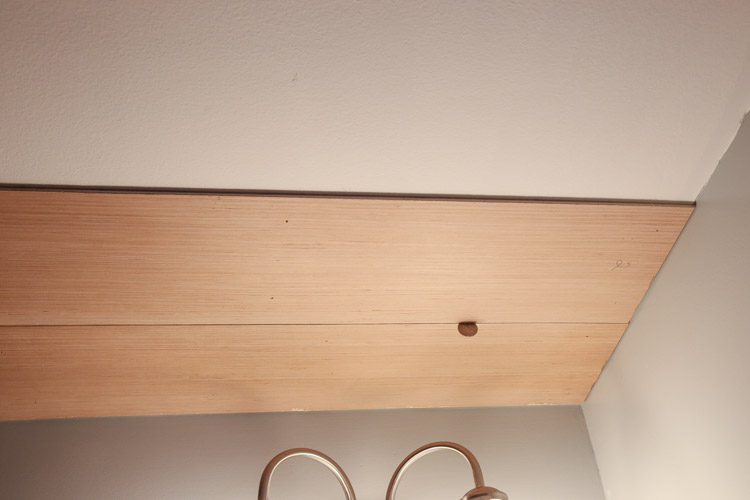A quarter being used a spacer for adding a gap between two shiplap boards on ceiling