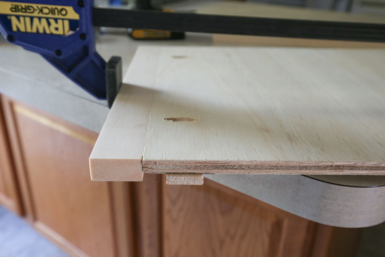 A clamp used to attach 1x2 board to plywood board with pocket holes
