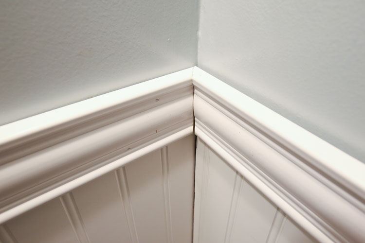 bathroom wall corner with two moulding pieces connecting at a 45 degree angle