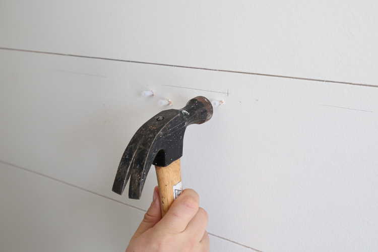 tapping the wall anchors into the holes with a hammer