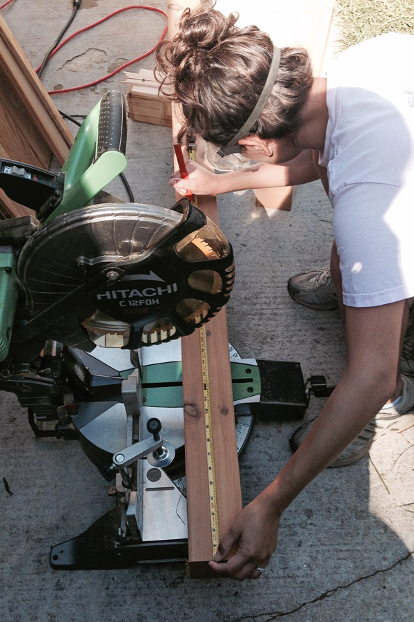 woman woodworker measuring wood on a miter saw