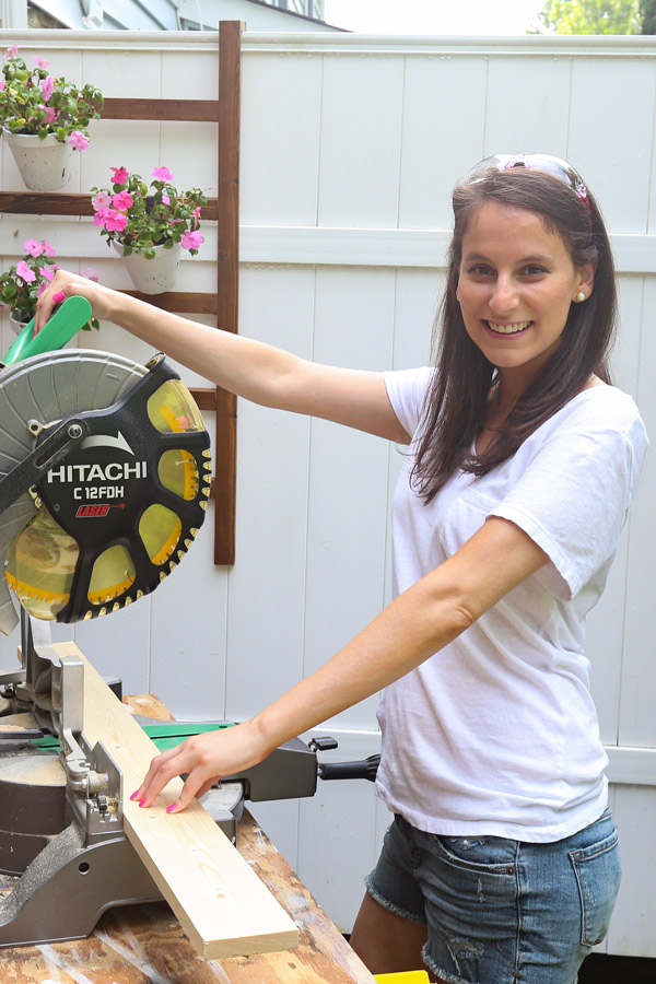 woman woodworking with a miter saw and pink saftey glasses