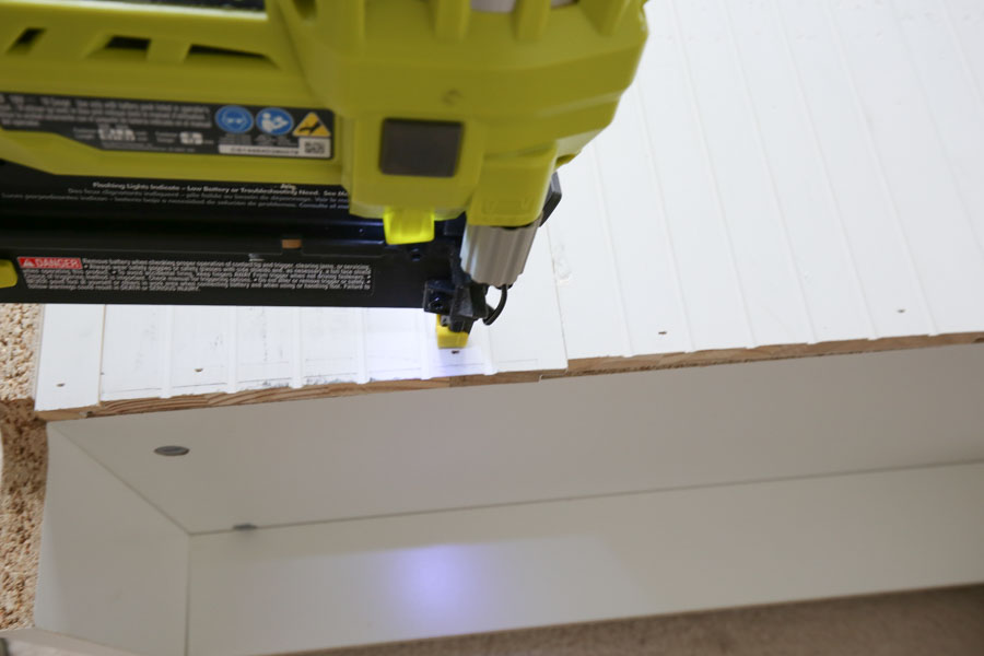 Using a brad nailer to attach shiplap boards to back of bookcase