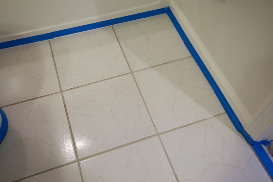 Painters tape being used to tape off the floor trim and bathtub