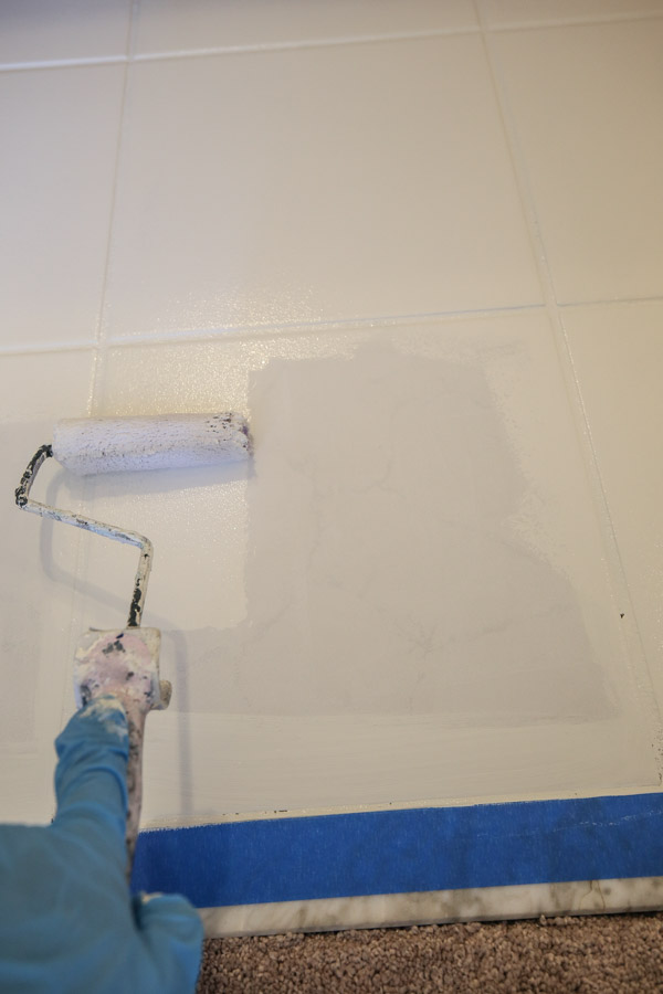 painting ceramic tile floor in a bathroom with a paint roller