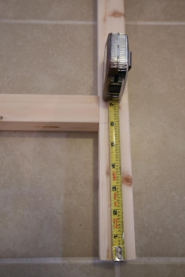 Using a tape measure to measure bottom wood support brace 6 inches up from ground