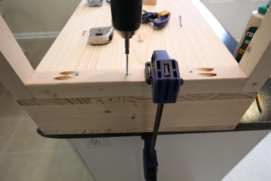 Using a drill and screws to add wood base board to the bottom of the vanity top