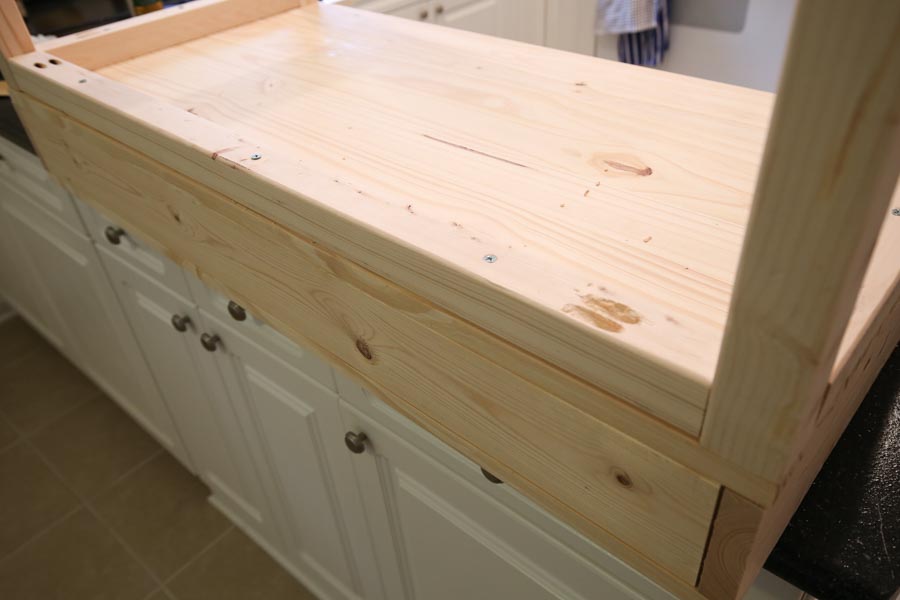 Using a drill and screws to add wood base board to the bottom of the vanity top