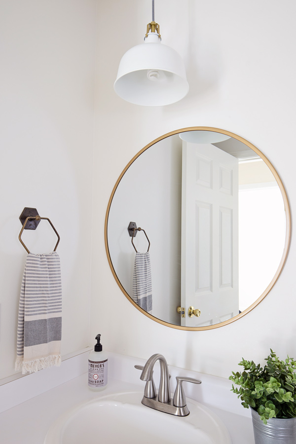 round gold mirror and white and gold pendant light over bathroom sink