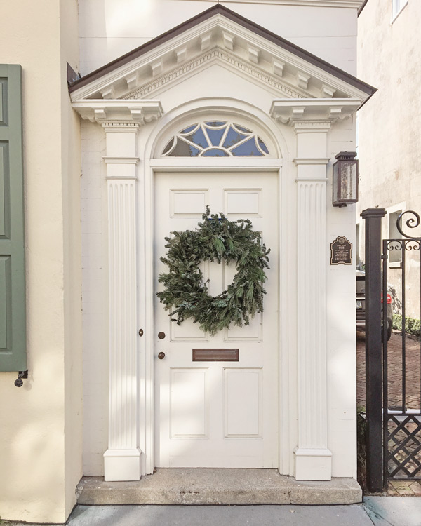 bushy green Christmas wreath on white front door in Charleston