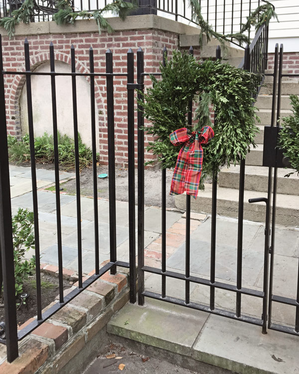 boxwood wreath with red plaid bow on iron fence in Charleston for Christmas decor