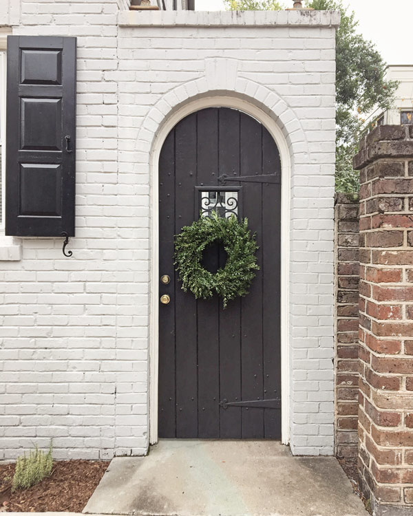 Simple boxwood wreath on black door in Charleston for Christmas decor