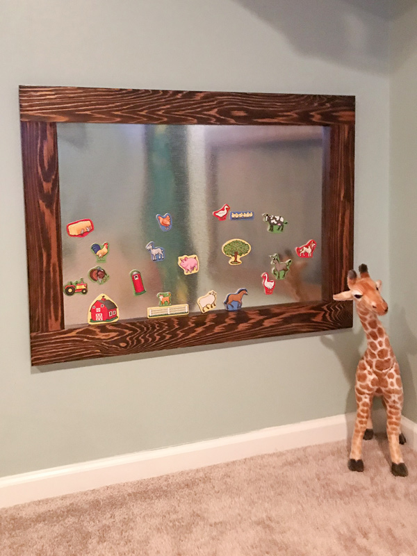 DIY magnetic board with kids magnets hung low on wall in kids playroom