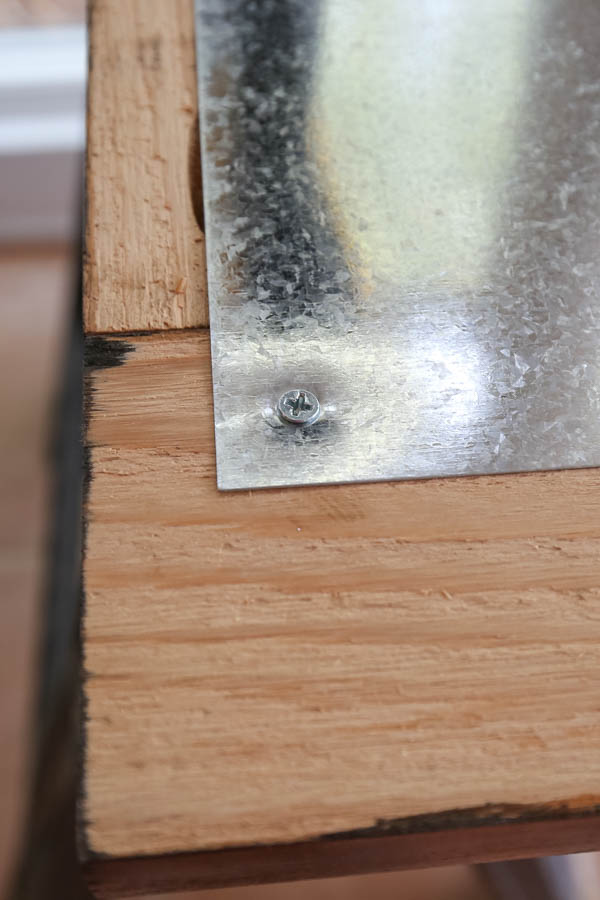 Sheet metal attached to magnet board wood frame with screws along edge