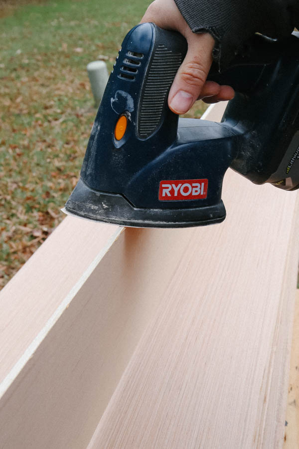 sanding edge of shiplap board with electric sander