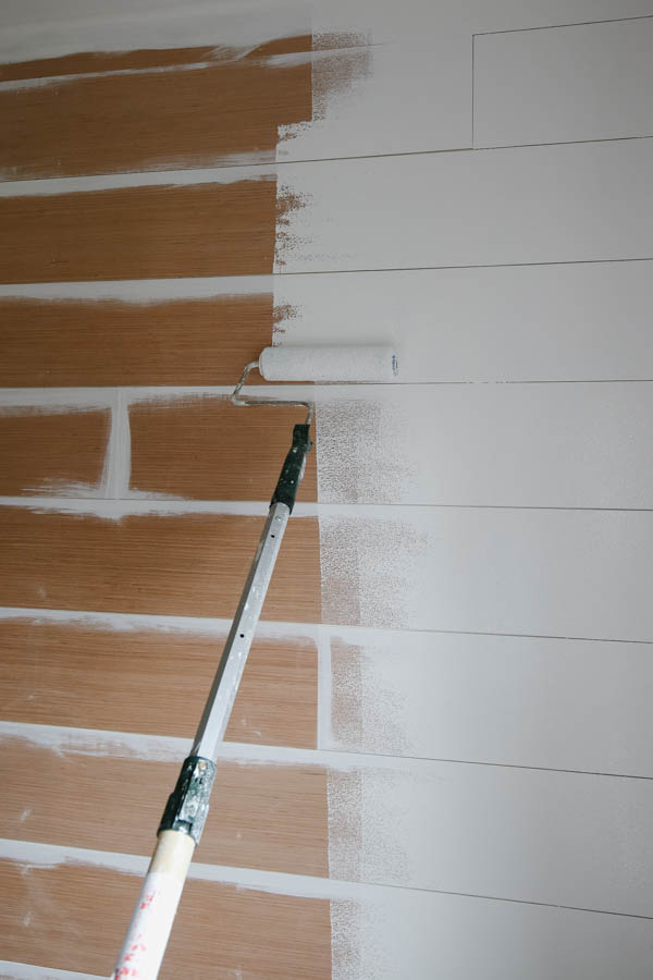 Rolling a shiplap wall with white paint and paint roller