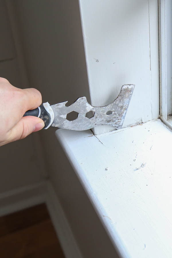 Removing old window sill by starting with utility knife to score the the caulk line edges