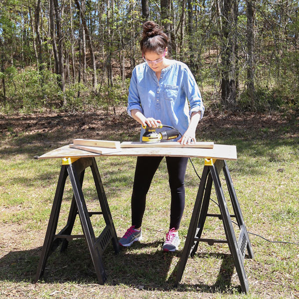 how to sand wood with woman sanding wood outside with orbital sander