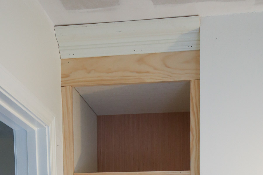 Install crown molding to the top of the DIY built in shelves with brad nails