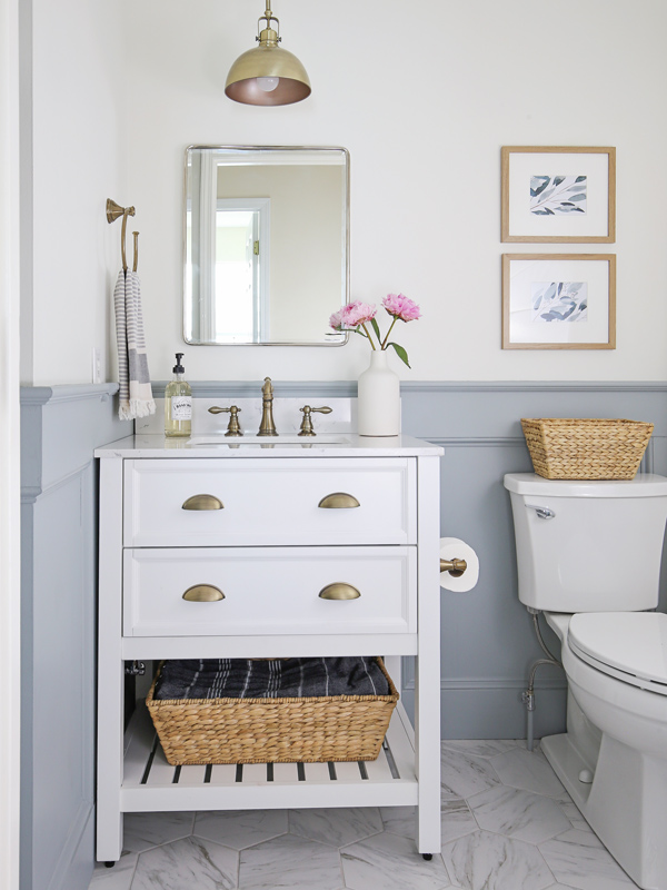 DIY small bathroom makeover with porcelain marble floors, white vanity, and blue gray wainscoting