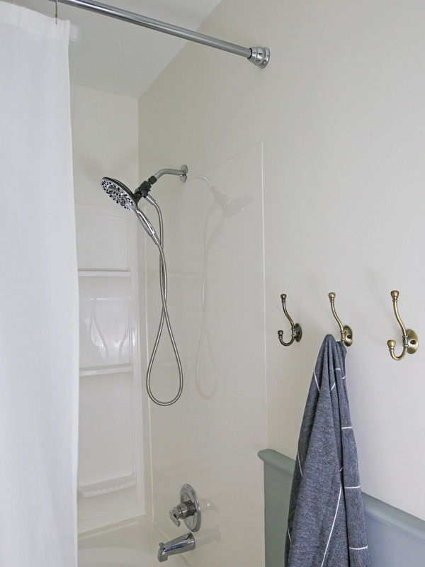 new shower surround and fixtures with brass towel hooks