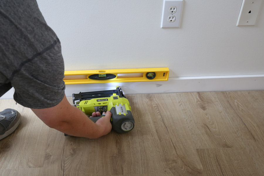 install new baseboard with level, brad nails, and brad nailer