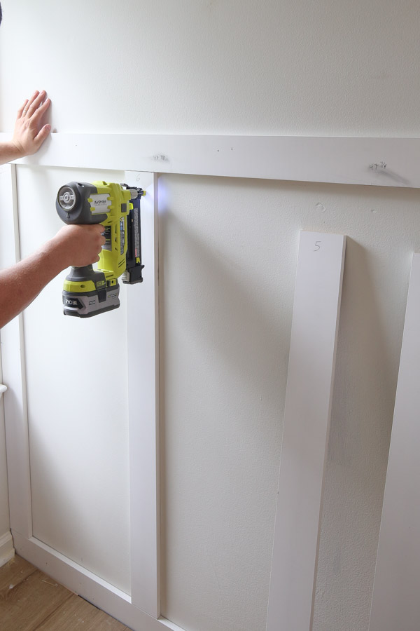 using a brad nailer to attach batten boards to wall for DIY board and batten