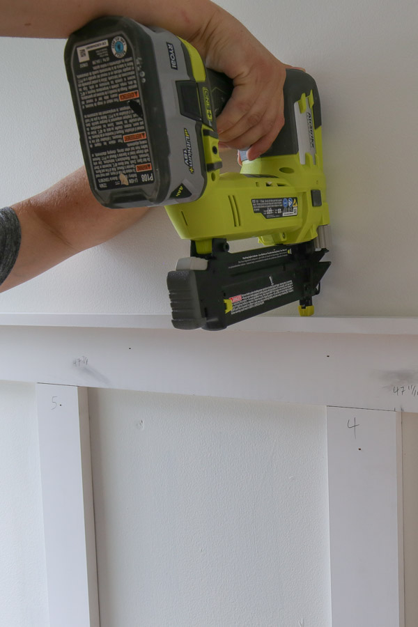 using a brad nailer to attach top 1x2 ledge board for diy board and batten accent wall