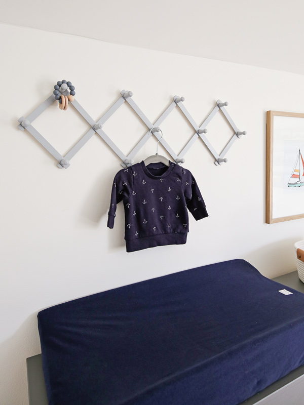 nursery changing station with accordion peg rack on wall