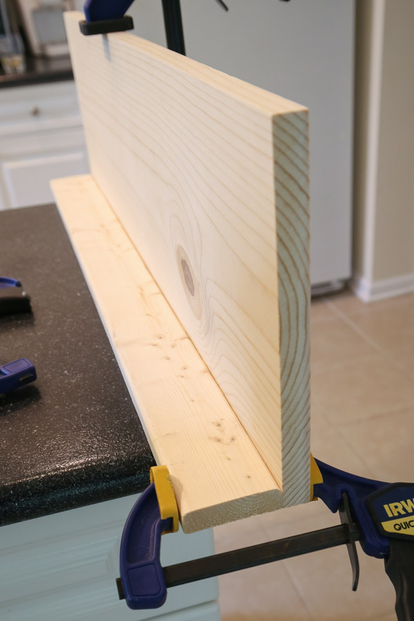 attach base board of DIY bookshelf wall wall backing board with brad nailer and wood glue and clamp