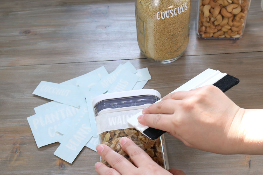 apply diy pantry cricut labels to jars with vinyl squeegee