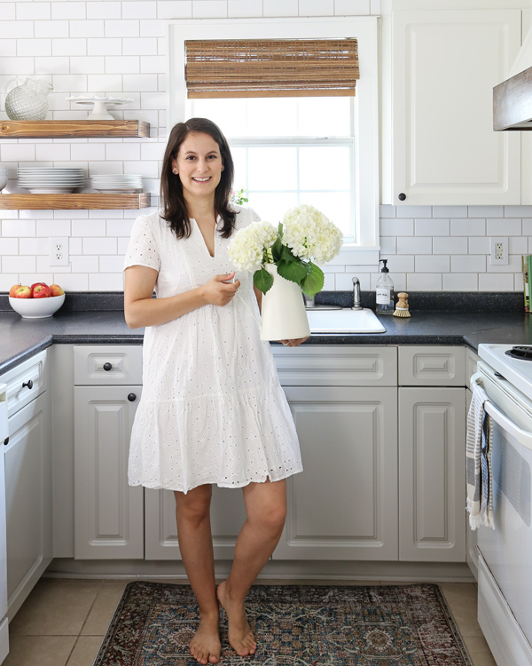 holding pitcher of flowers in renoavted kitchen