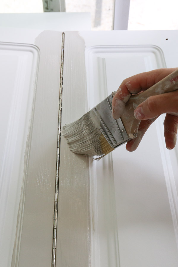 painting kitchen cabinets with a paint brush to cut in