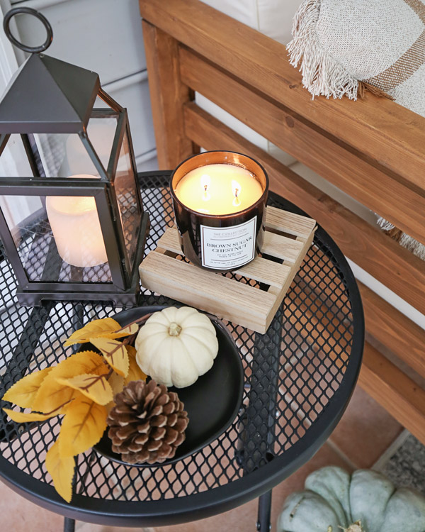 fall decor on side table with mini white pumpkin, fall candles, leaf stem, and pinecone