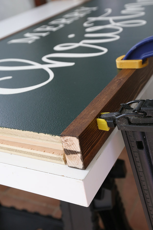 using a brad nailer to attach frame board to Christmas sign DIY