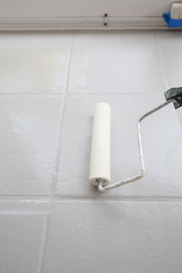 using a roller to apply the top coat over painted tile floor