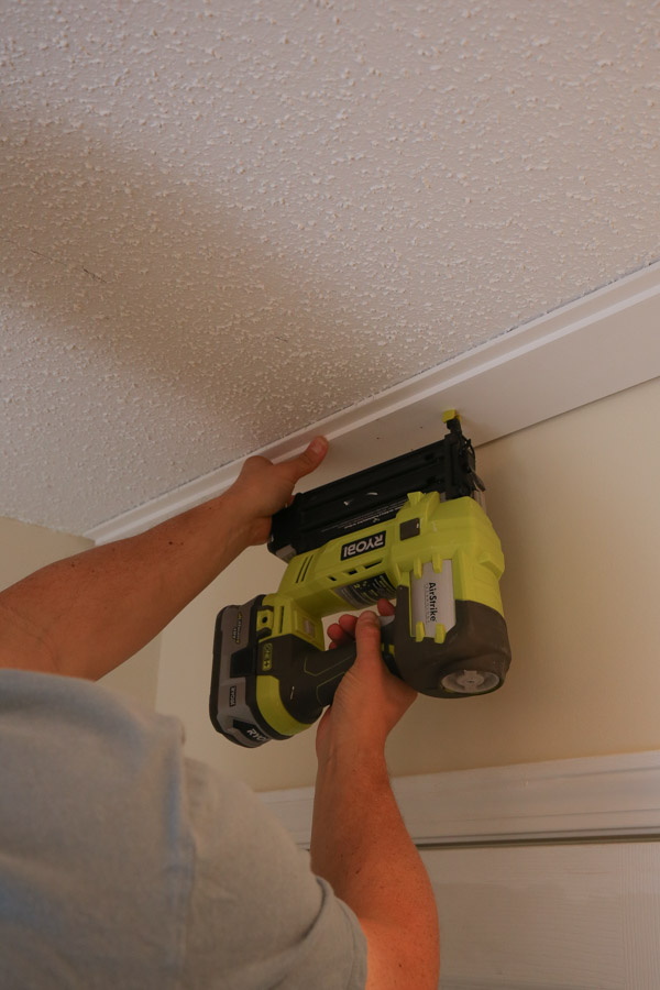 installing first shiplap board to ceiling with brad nailer