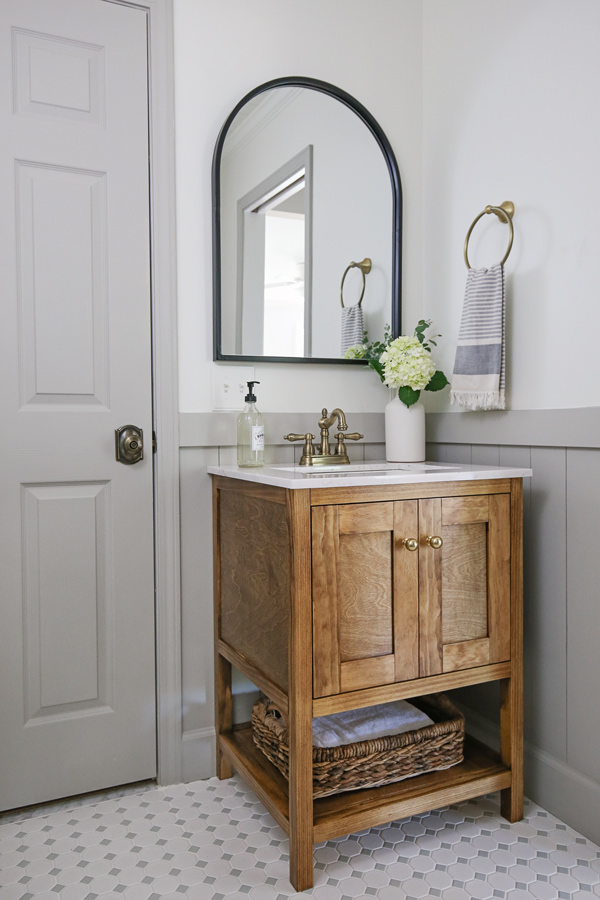 DIY bathroom makeover reveal with vertical shiplap, grey trim, wood bathroom vanity, and black arch mirror