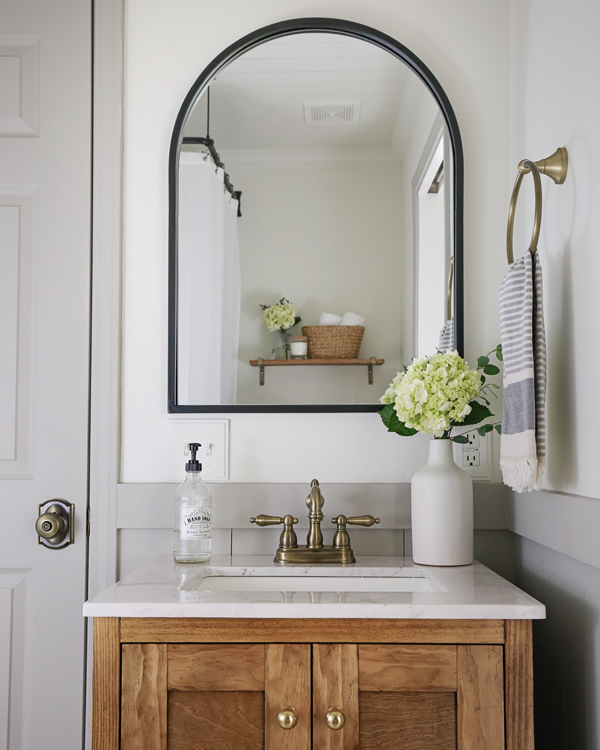 black arched mirror over wood bathroom vanity