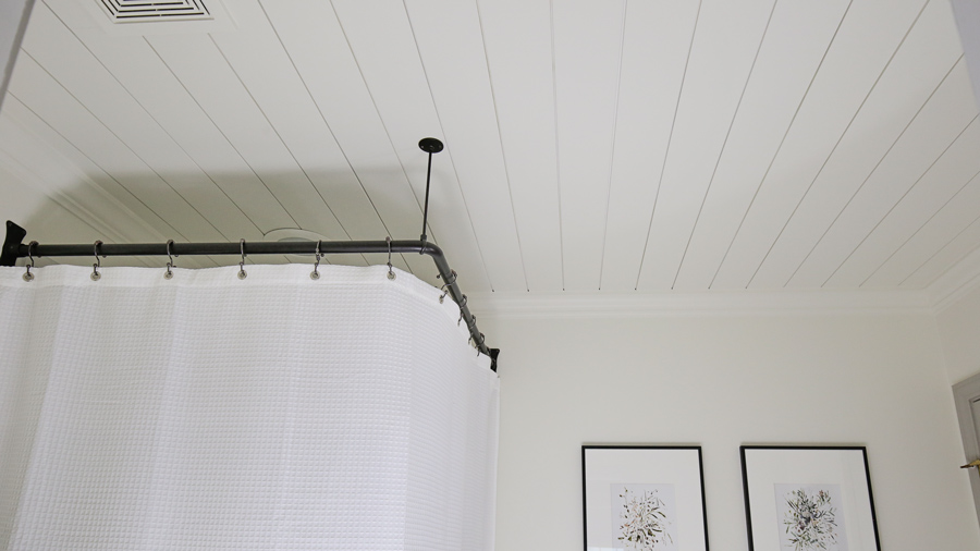 DIY shiplap ceiling in a bathroom with corner shower rod