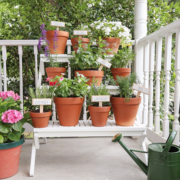 three tiered plant stand with flowers, herbs, and plants in pots