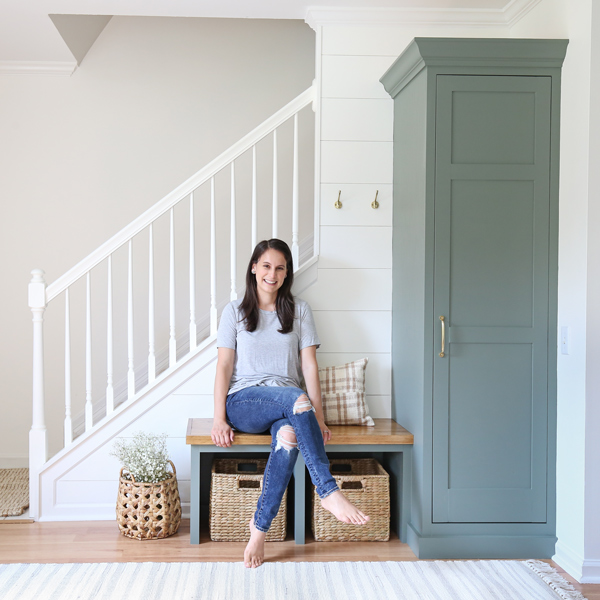 DIYer sitting on DIY built in bench in entryway makeover