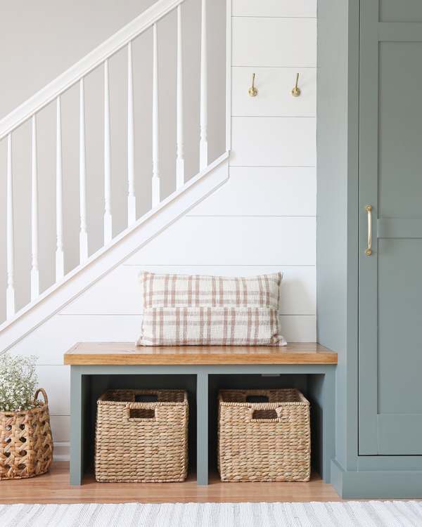 diy entryway bench built in with plaid pillow and brass wall hooks and DIY shiplap wall