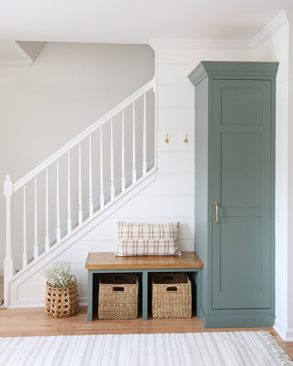 DIy entryway makeover with green painted built ins and large 3 panel DIY cabinet door, DIy shiplap, and white painted stair railing