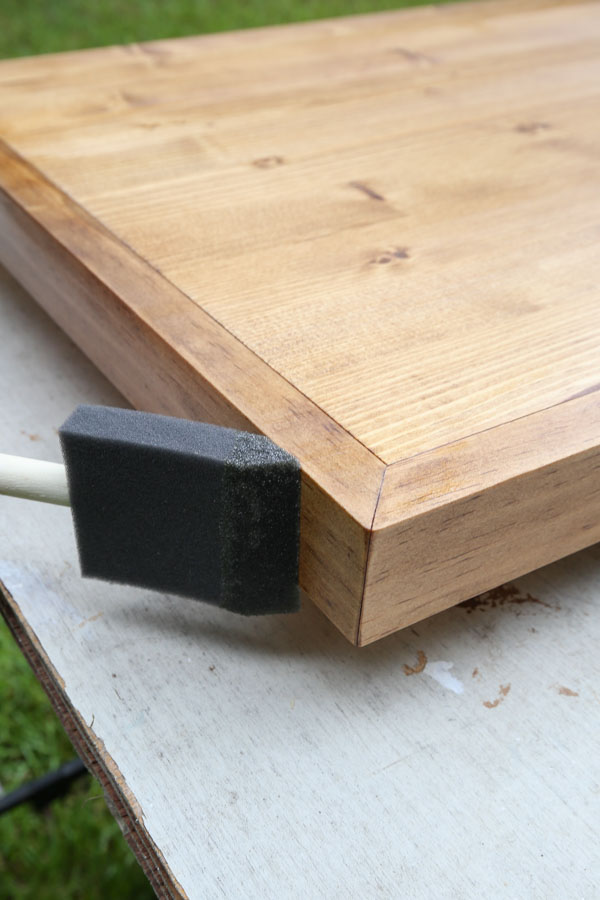 applying polyurethane to side edge of wood with foam brush